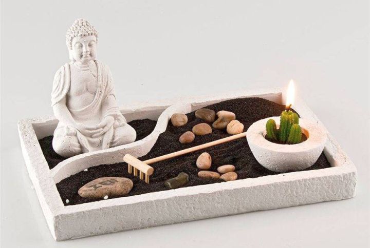 zen style mini japanese garden with black sand and Buddha statue